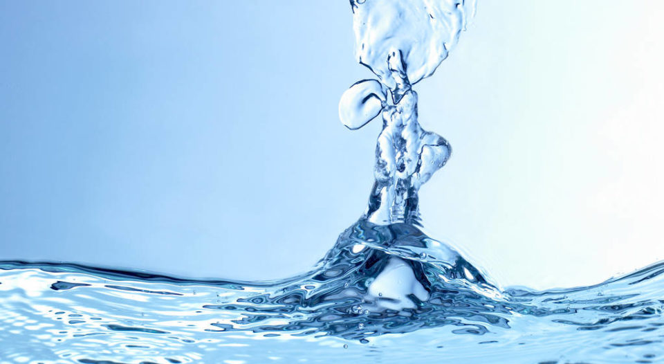 A drop of water plunges into a body of water, creating a ripple effect