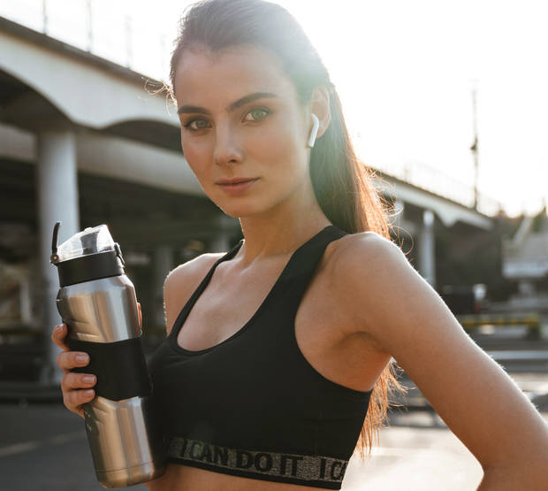 Sports fitness woman outdoors drinking water.