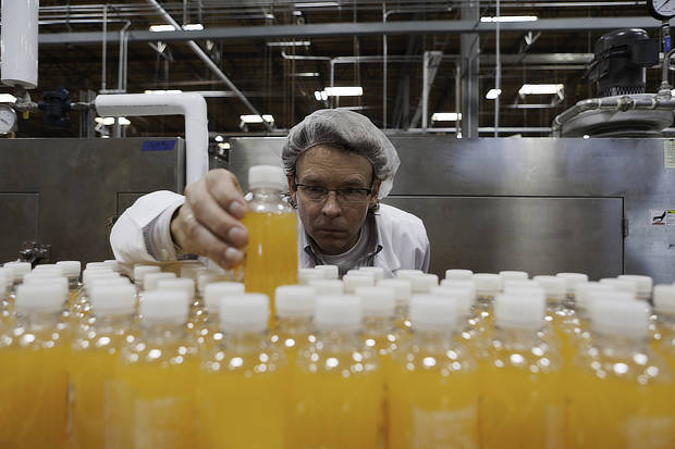 Industrial worker examining bottle in factory