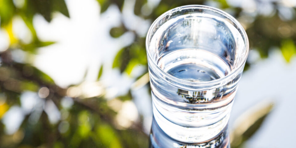 Refreshing water in transparent glass with reflection against bl